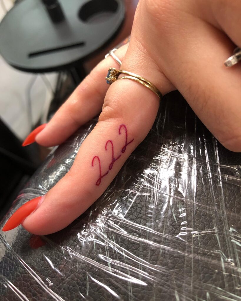 222 in Handwriting Style Tattoo in Red Color on the Side of the Middle Finger, a Personal Touch: Handwritten Harmony 