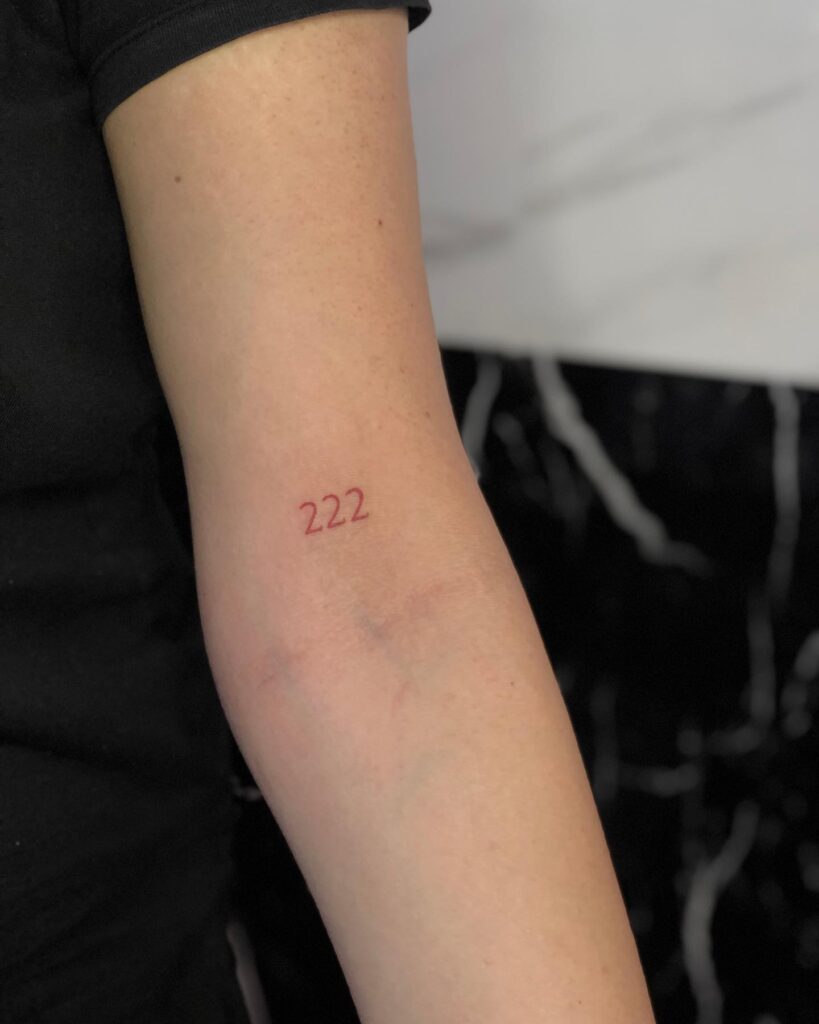 222 Red Color Text Tattoo Above the Inner Elbow: Inner Elbow Expression, a Unique Placement