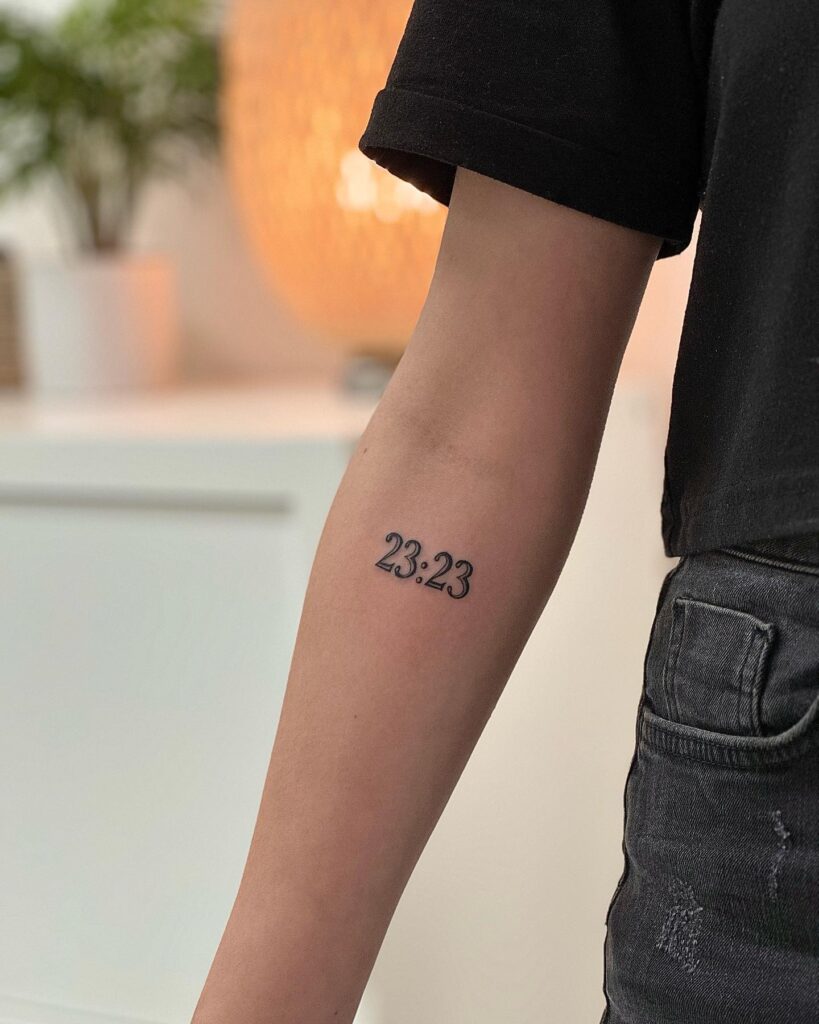 '23:23' Text Tattoo on the Below the Elbow: Time's Embrace