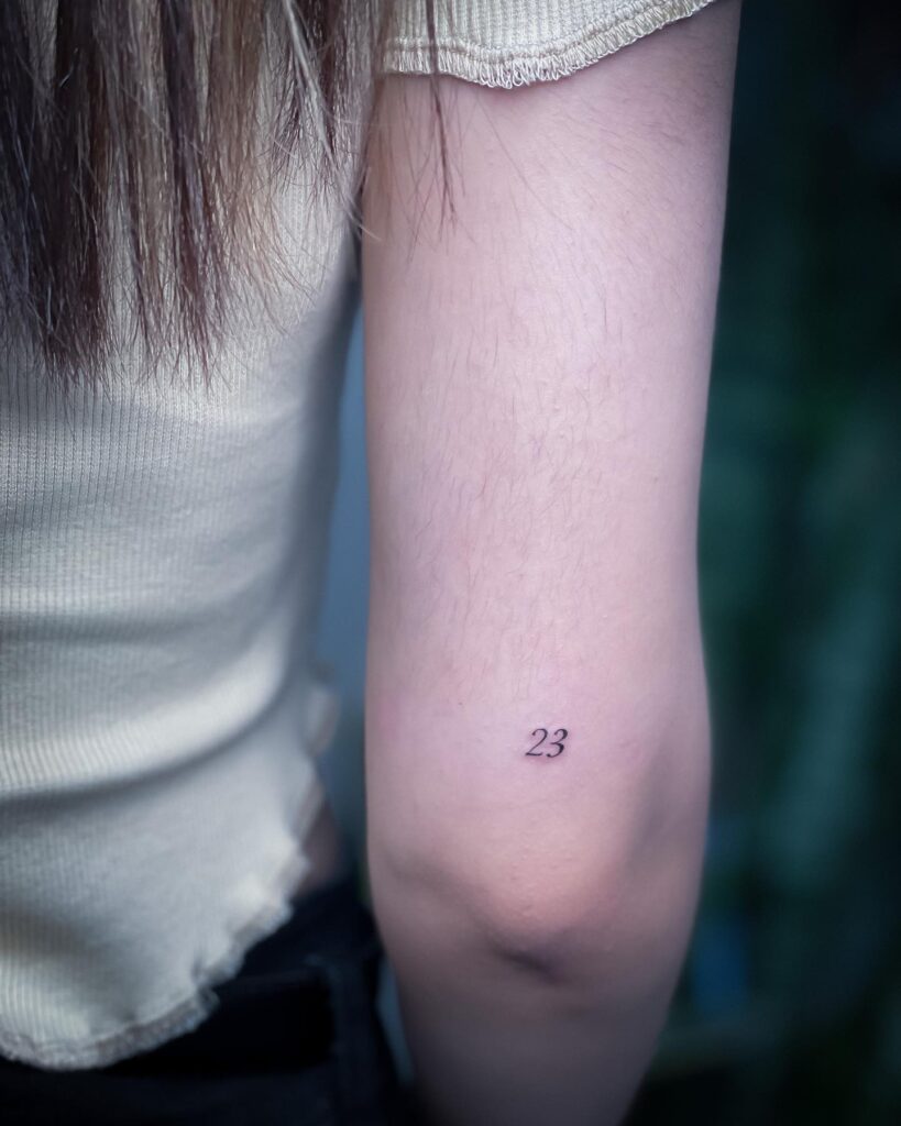'23' Text Lettering Small Tattoo on the Back of the Elbow Above Tattoo: Numerical Whispers