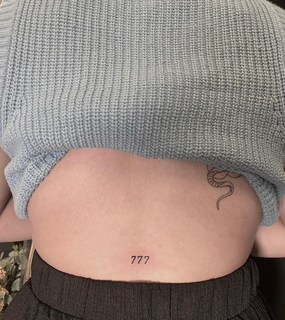 777 angel number fineline tattoo on lower back a subtle yet cool design for females luminescent luck 