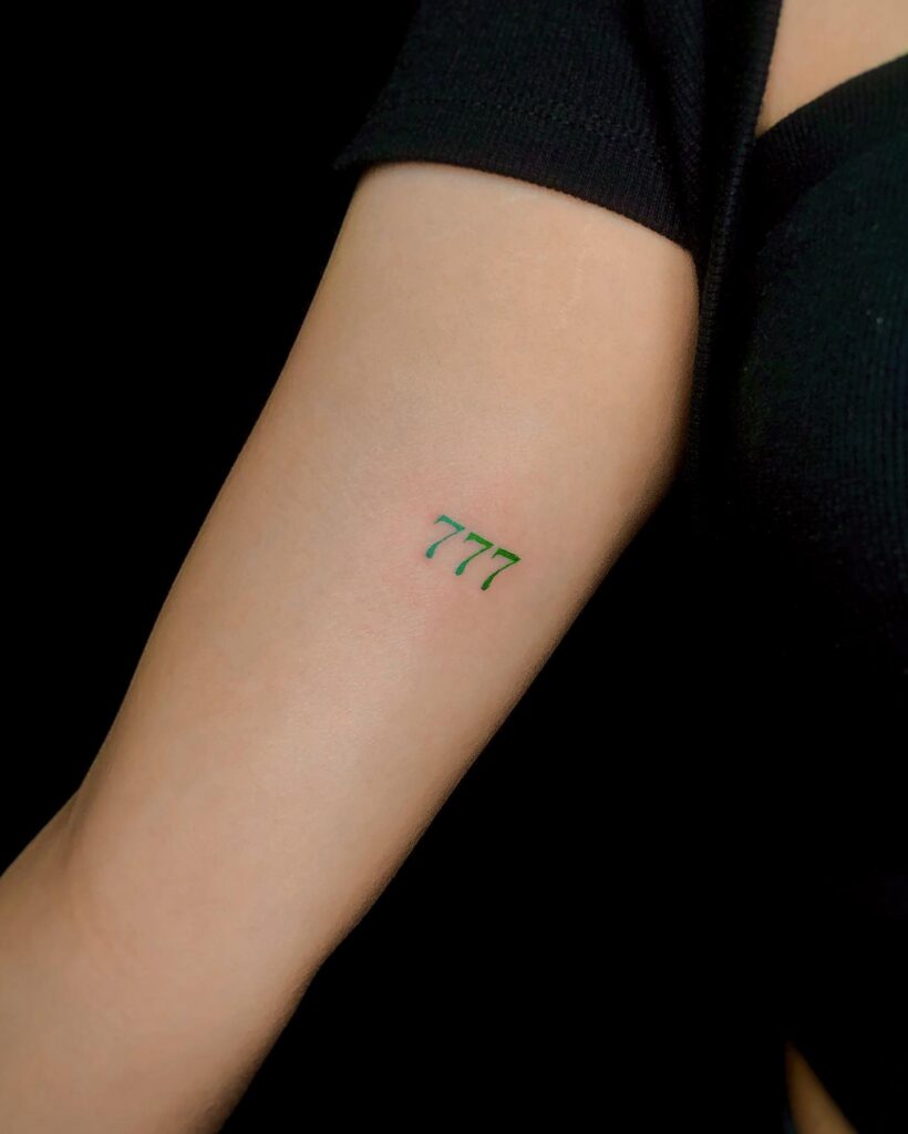 777 number on the biceps adding a touch of colorful elegance to the ink emerald essence 