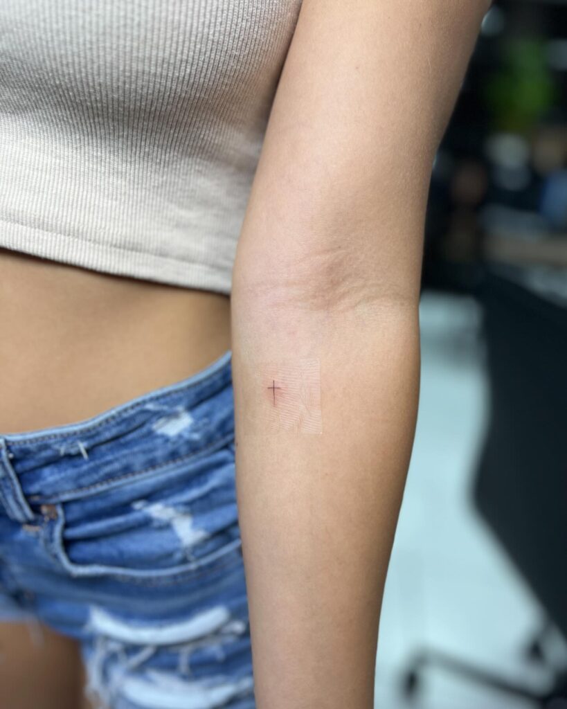 Whisper-Thin Cross Tattoo Below the Elbow: A Subtle Symbol of Faith