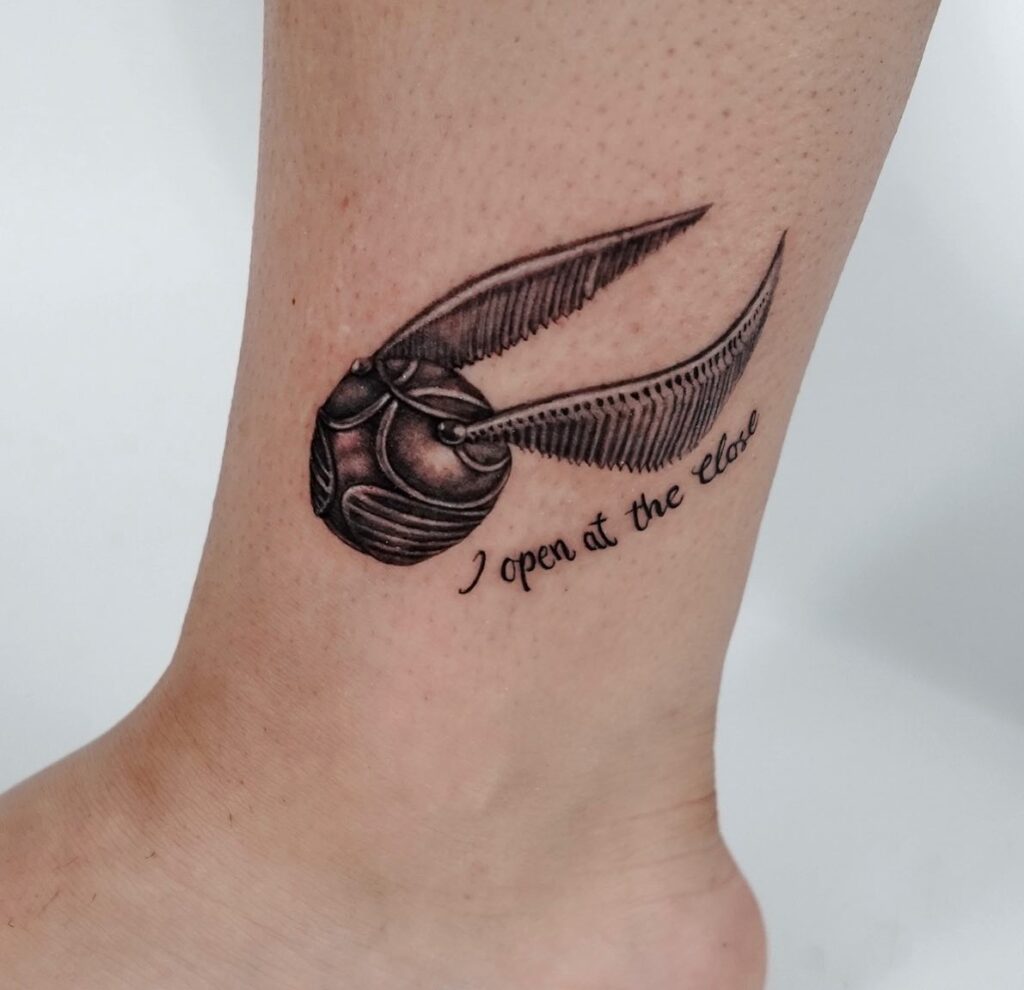 Above the ankle enchantment golden snitch tattoo with 'I open at the close' text