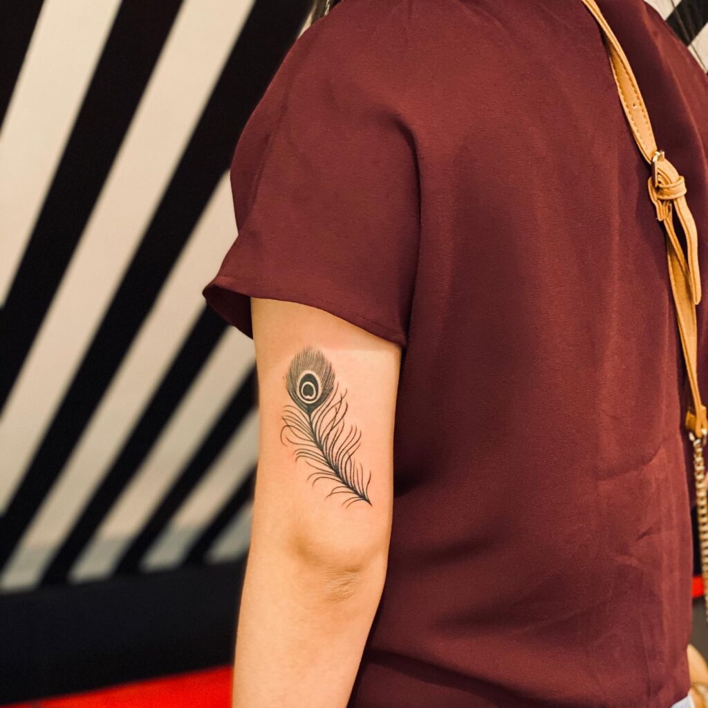 Above the elbow chic outer arm peacock feather tattoo for women