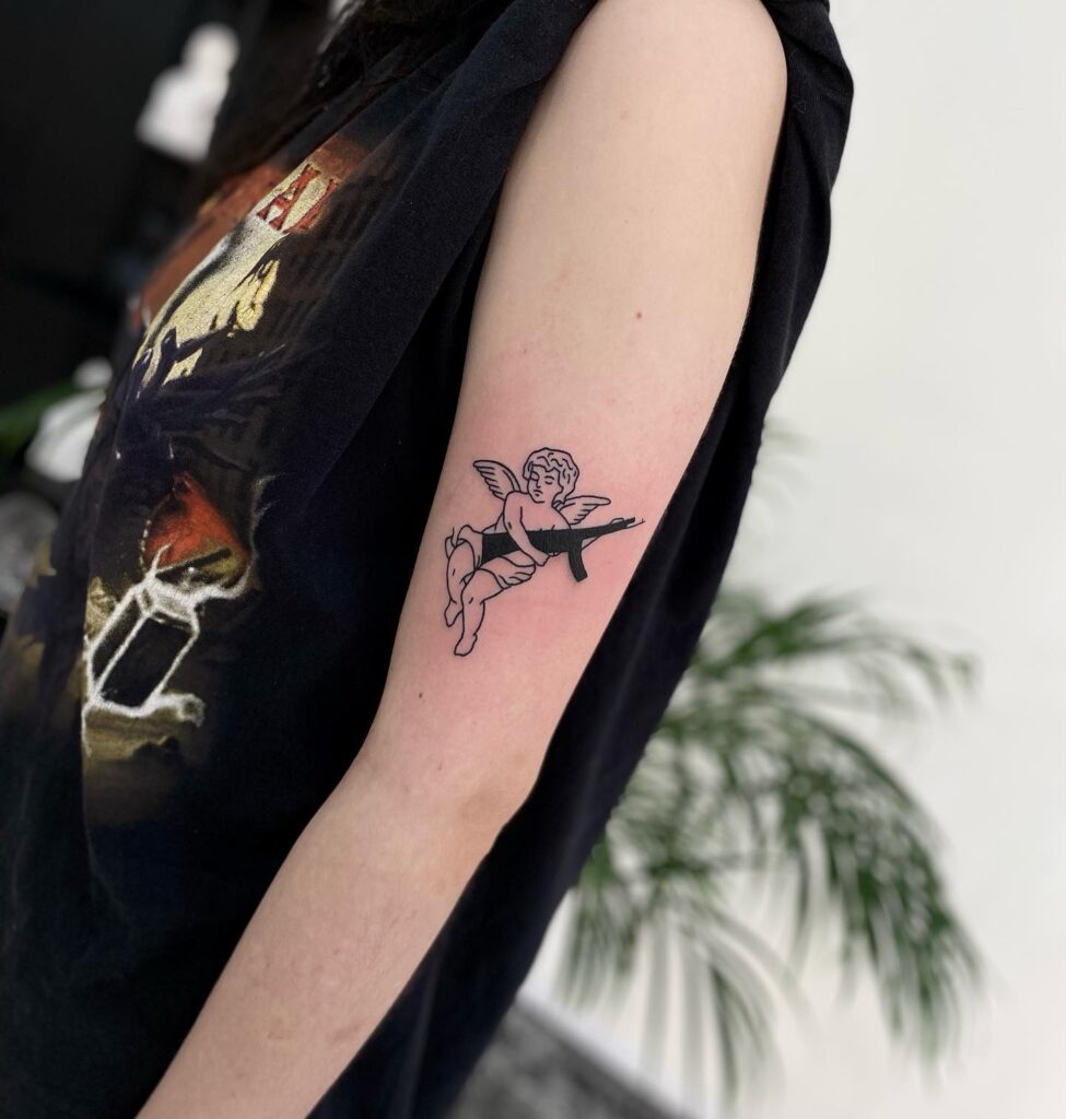 Above the elbow side angel with gun tattoo on the upper arm a unique statement