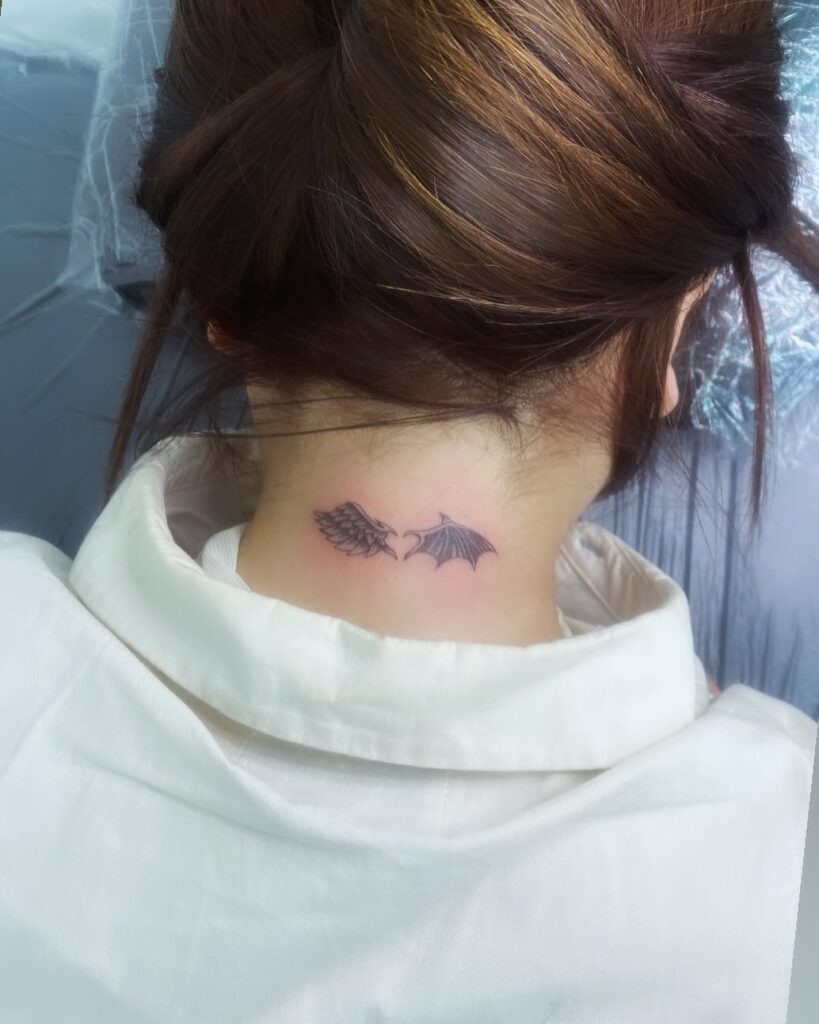 Angel and demon wings tattoo on the back of the neck symbolizing duality