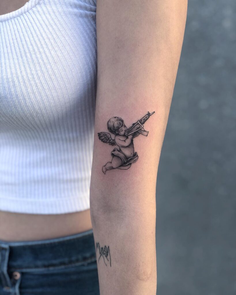 Angel Baby with Gun Tattoo Above the Elbow: Celestial Marksman