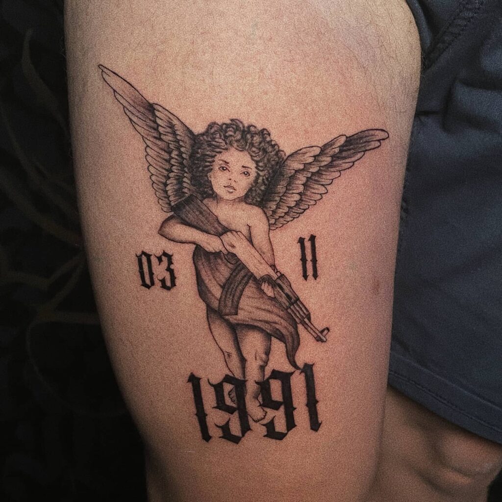 Angel with gun thigh tattoo with date 03 11 1991 a personal tribute in ink