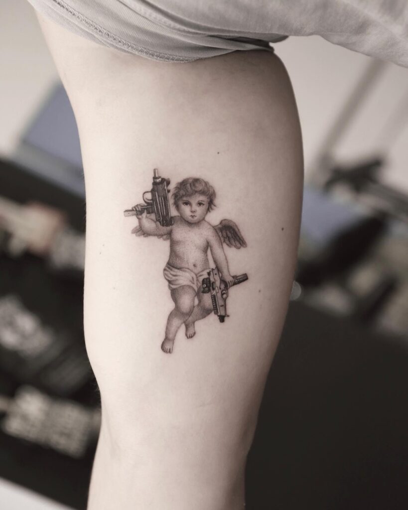 Angel with guns tattoo on biceps a display of strength and artistry