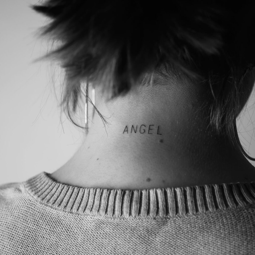 'angel' word tattoo on the back of the neck in subtle thin lines heavenly grace