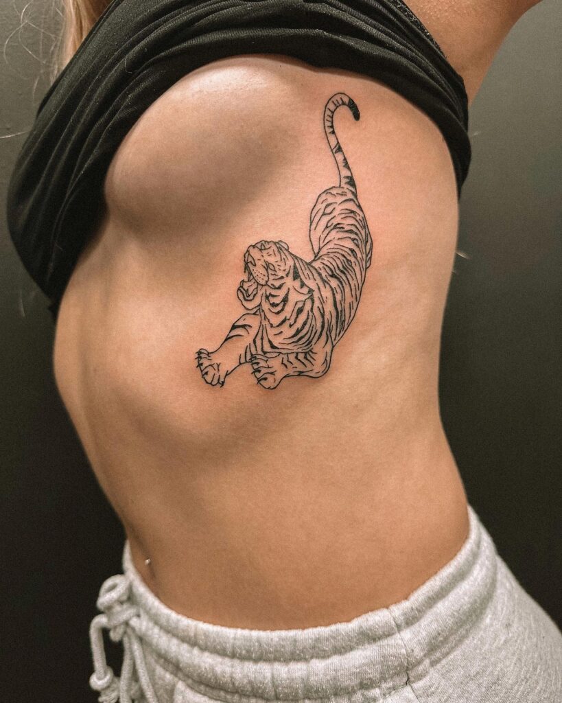 Angry realistic tiger tattoo with a high angle view on the rib: fierce stripes
