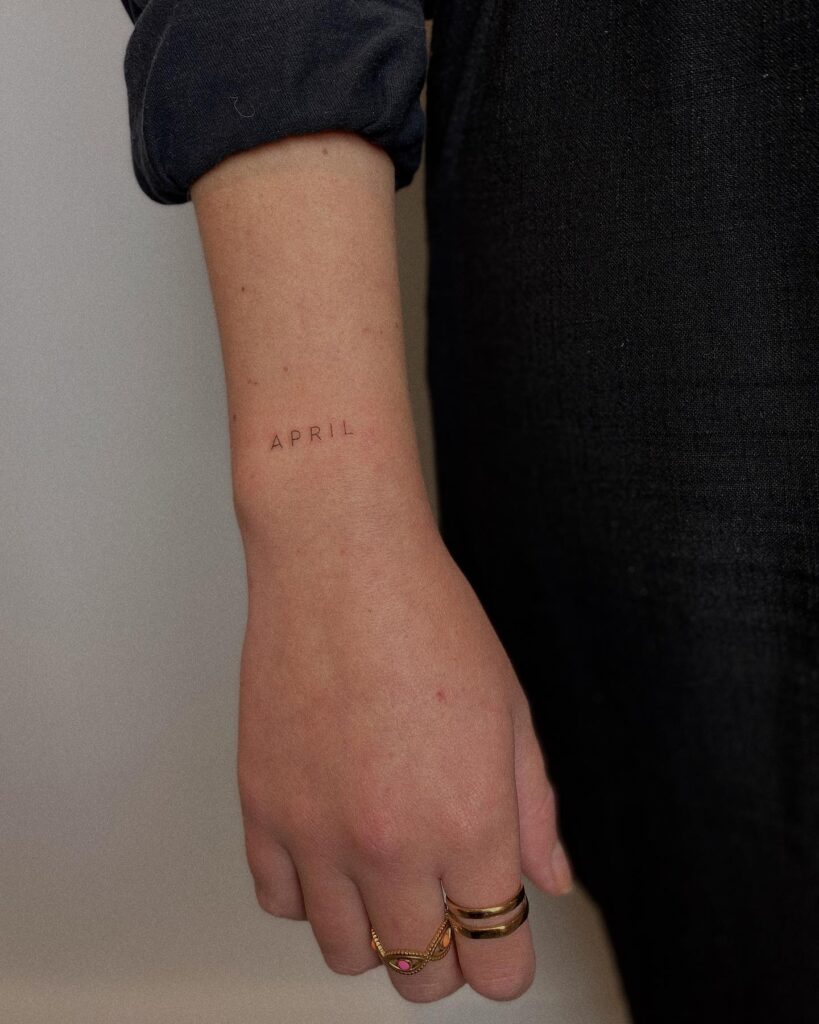 'APRIL' Lettering Tattoo on the Outer Wrist, a Sweet Tribute to a Birth Month: April Whispers