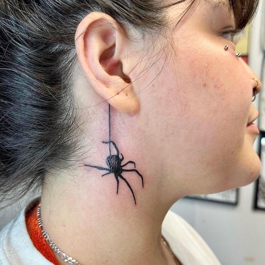Arachnid artistry black spider tattoo behind the ear and on the neck