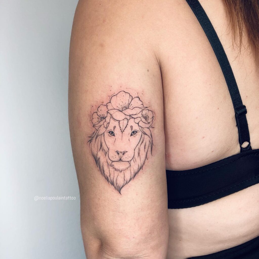 Back of the upper arm fineline tattoo, featuring a lion head above a bed of flowers for a cool and artistic expression blooming roar