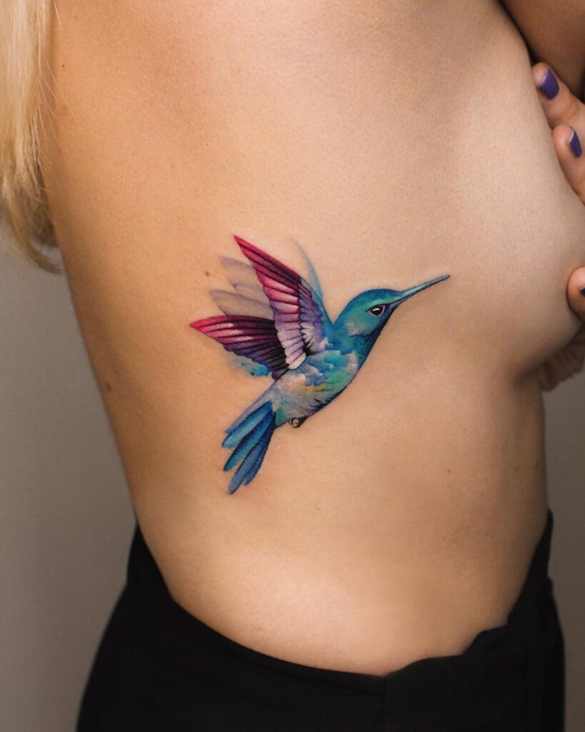 Beautiful colored hummingbird side view tattoo adding delicate beauty to the rib-hummingbird harmony