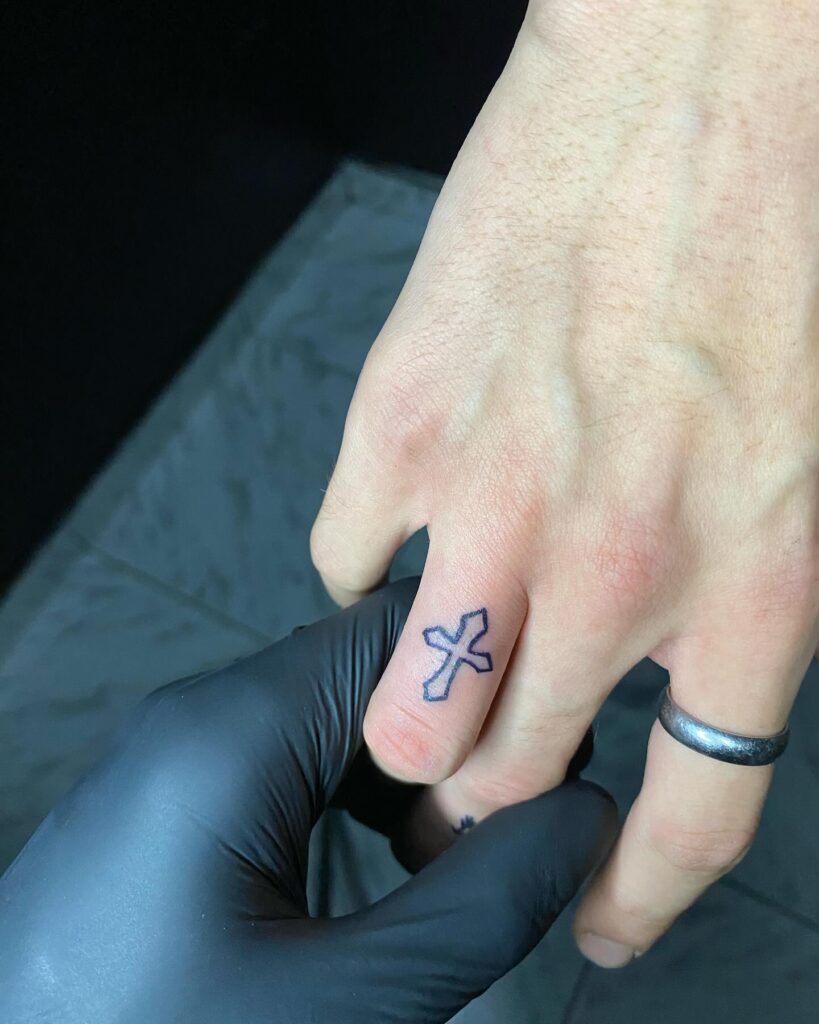 Beautiful simple cross tattoo on ring finger girl