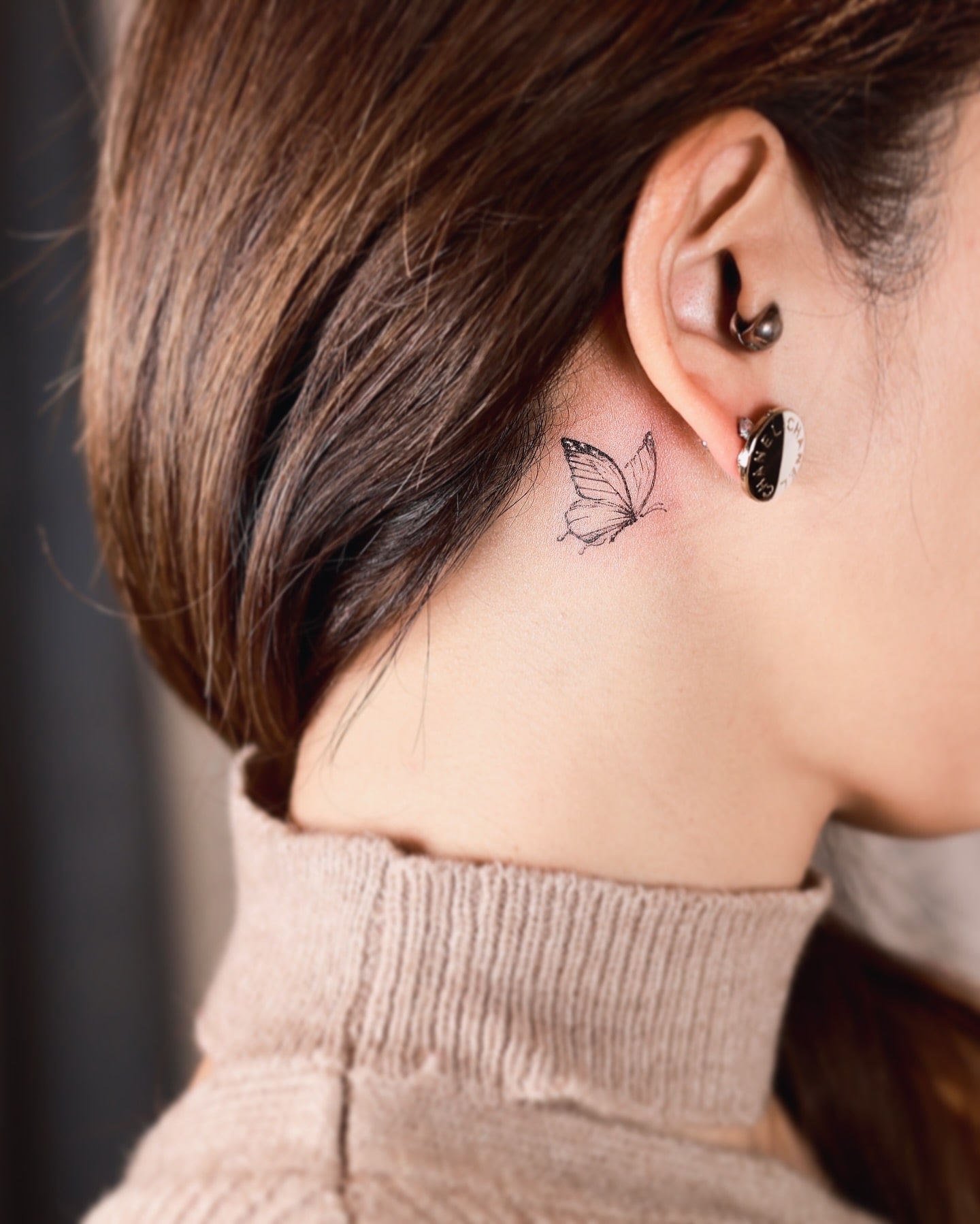 Behind the ear butterfly tattoo with delicate shading and spiritual symbolism