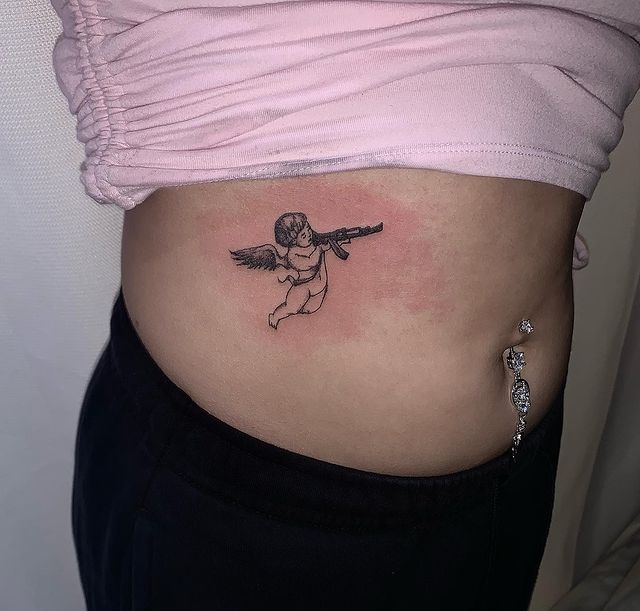 Belly angel with gun tattoo for women