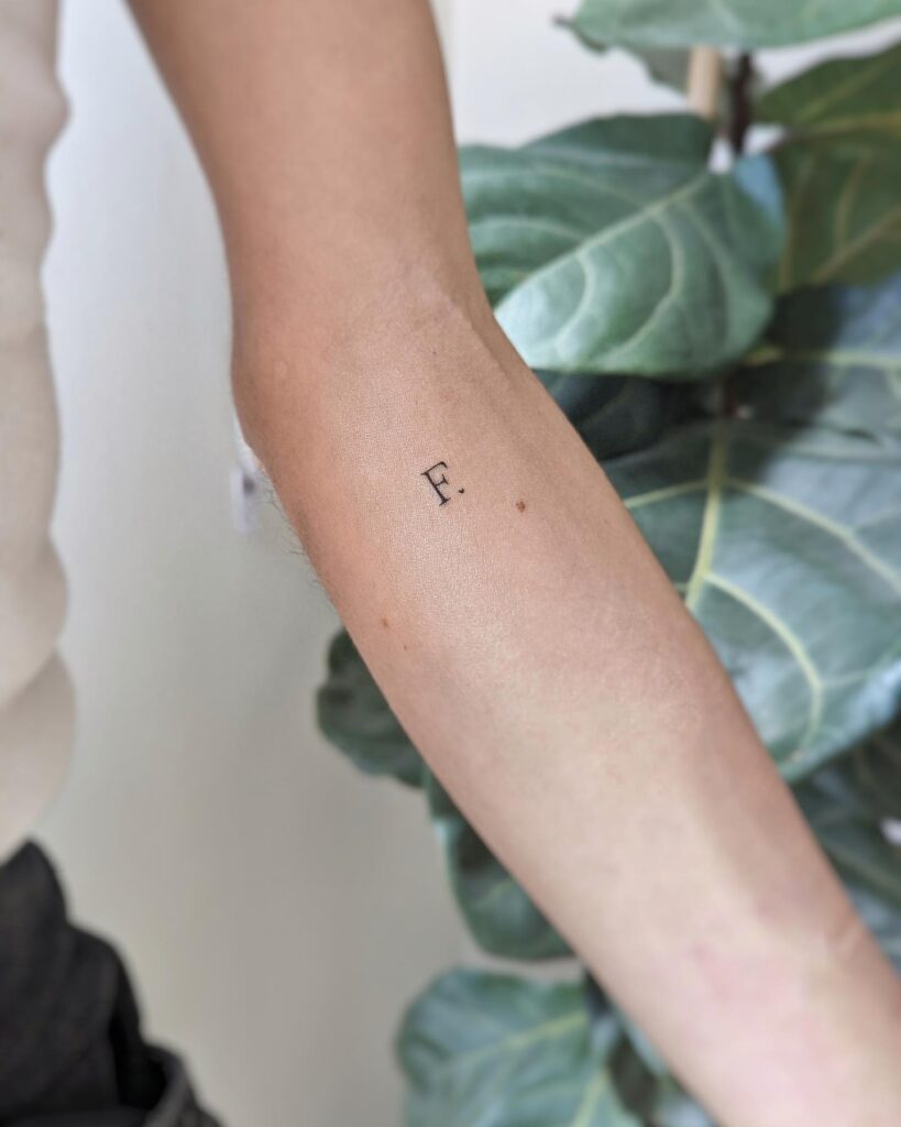 Below Inner Elbow 'F.' Text Lettering Tattoo: Elbow Elegance