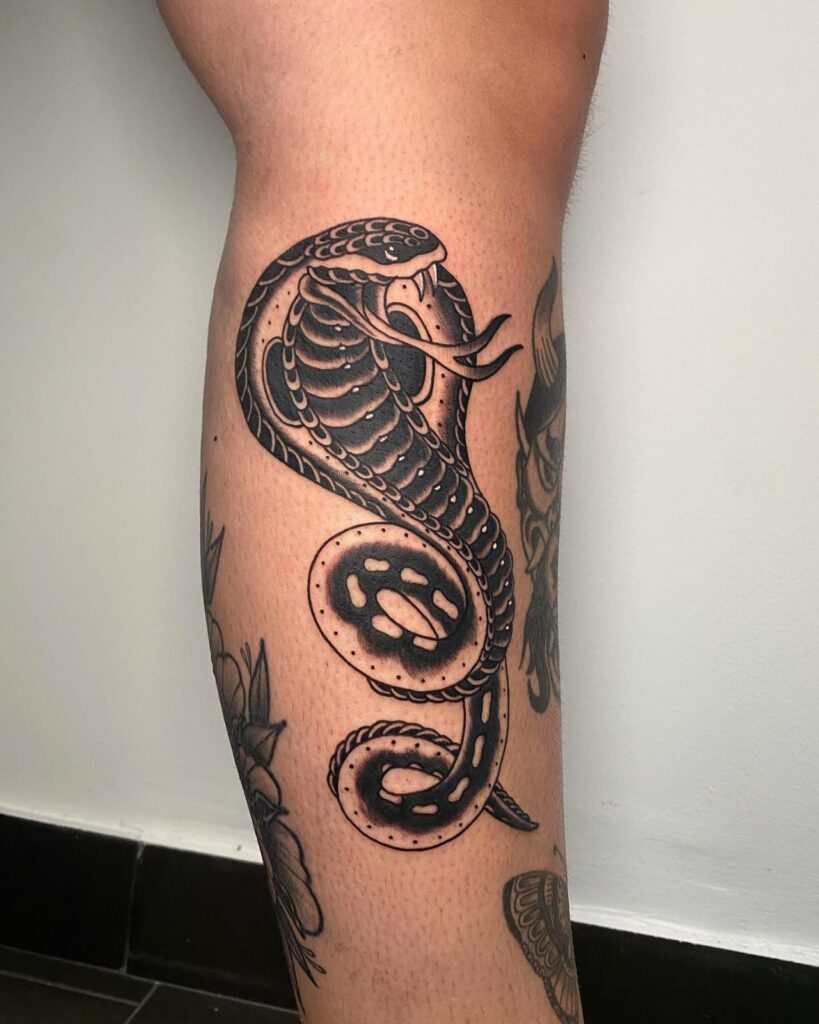 Black and gray cobra tattoo on lower leg sinister serpent in striking detail