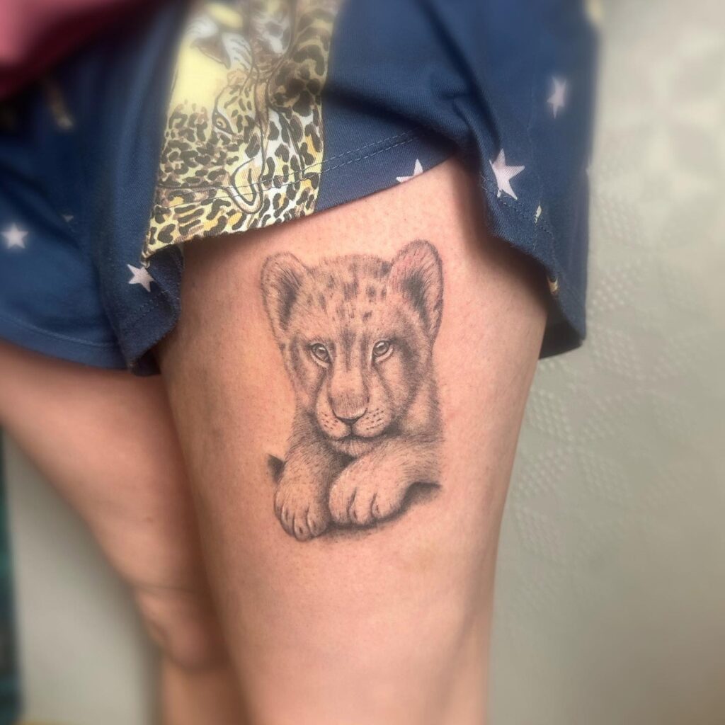 Black and grey cute cub tattoo on the thigh: cute cub charm
