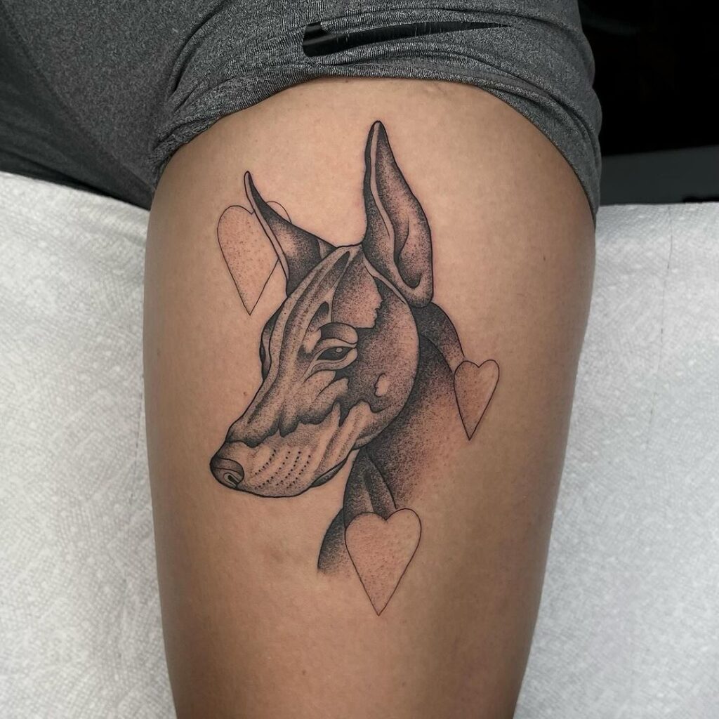 Black and grey doberman face portrait tattoo on the thigh dobie dreams