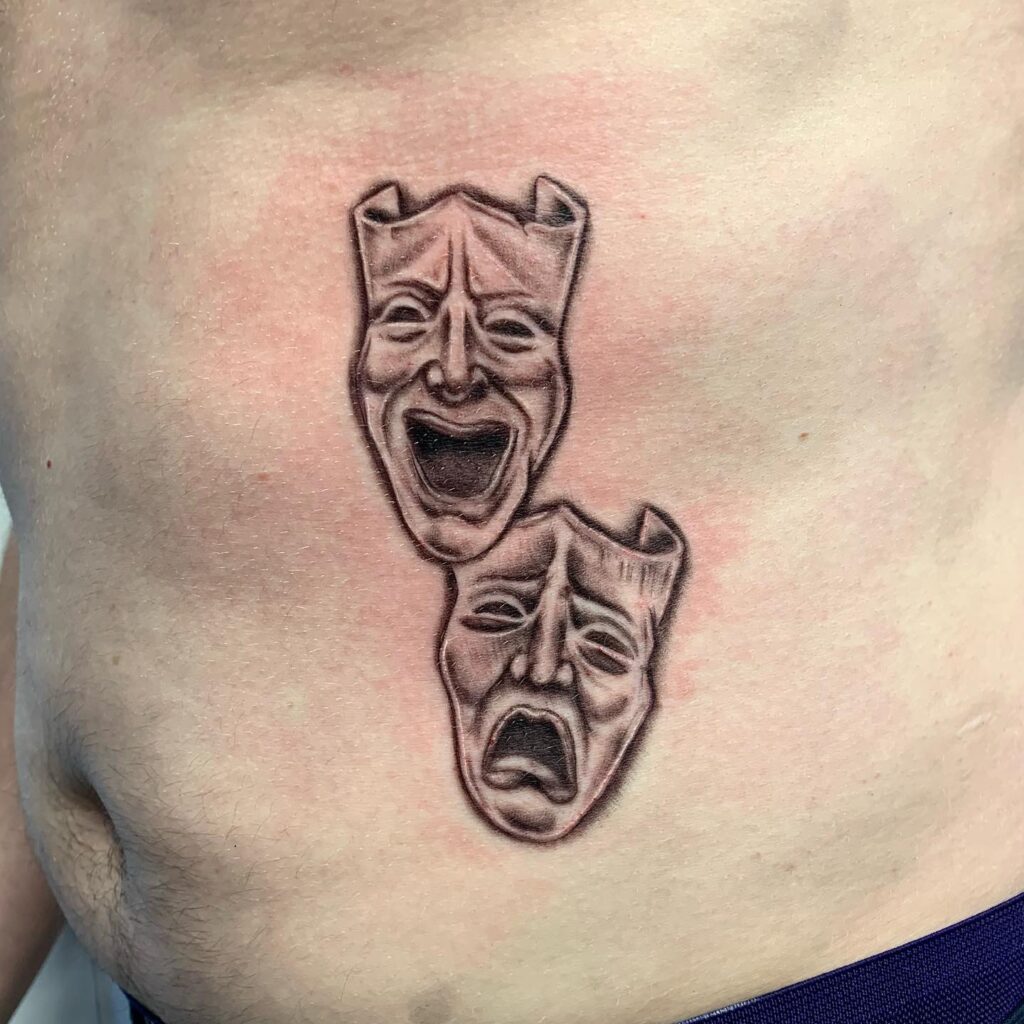 Black and Grey Laugh Now Cry Later Mask Tattoo on Side Stomach: Monochromatic Drama 