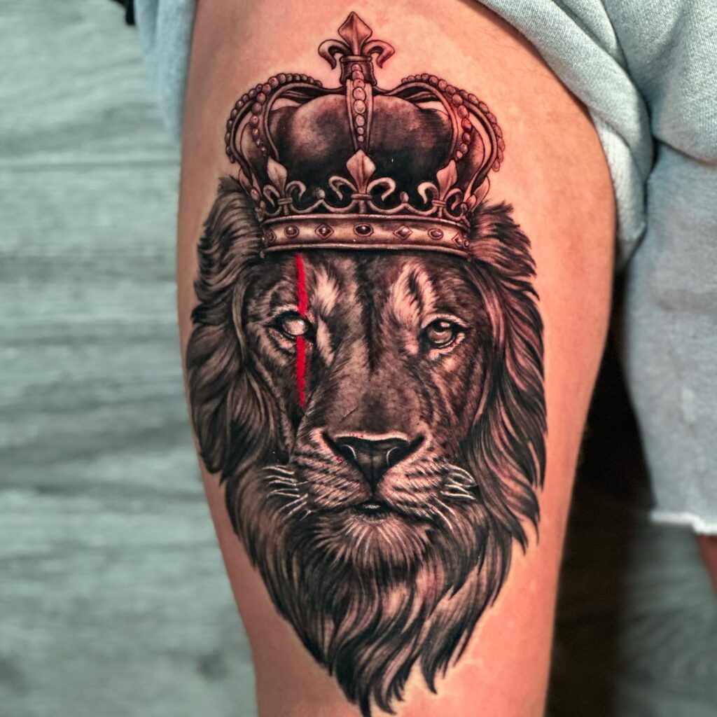 Black and grey lion head with crown on the upper arm: royal mane majesty
