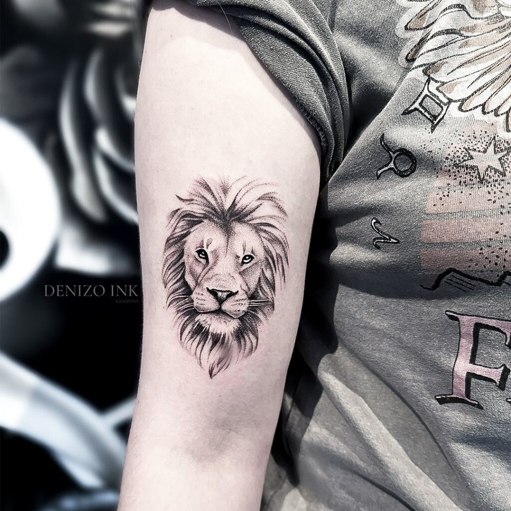 Black and grey mini lion face tattoo above the elbow for females: mini majesty