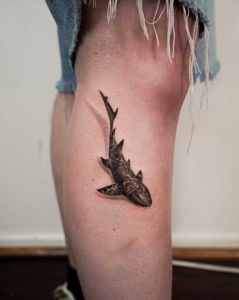 Black and grey realistic shark tattoo on leg featuring intricate shading and depth for a bold look