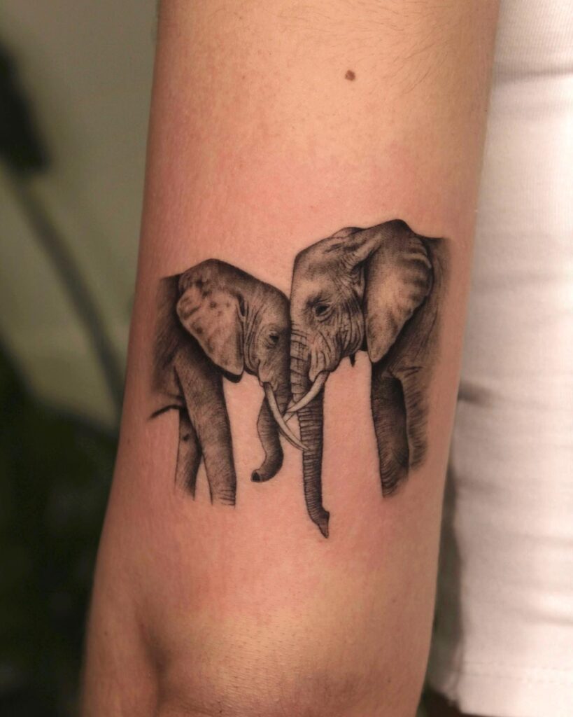 Black and grey shaded side view on back of the elbow: graceful elephants meet