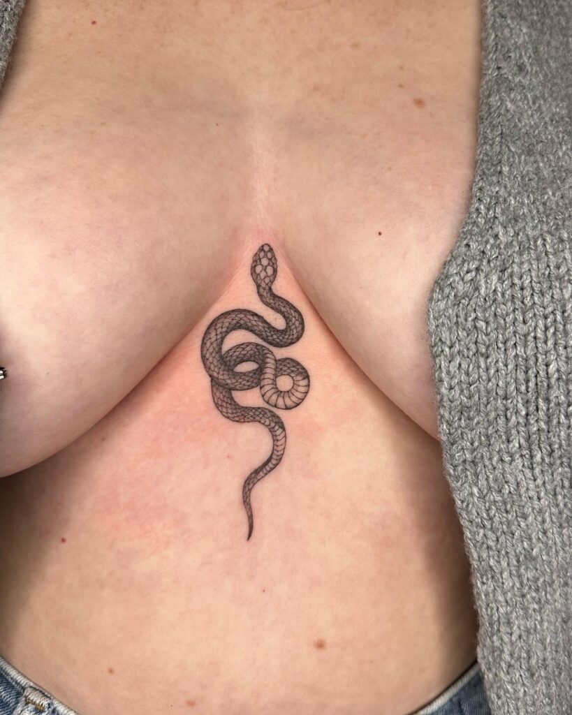 Black and grey snake sternum tattoo with fine linework and deep symbolism