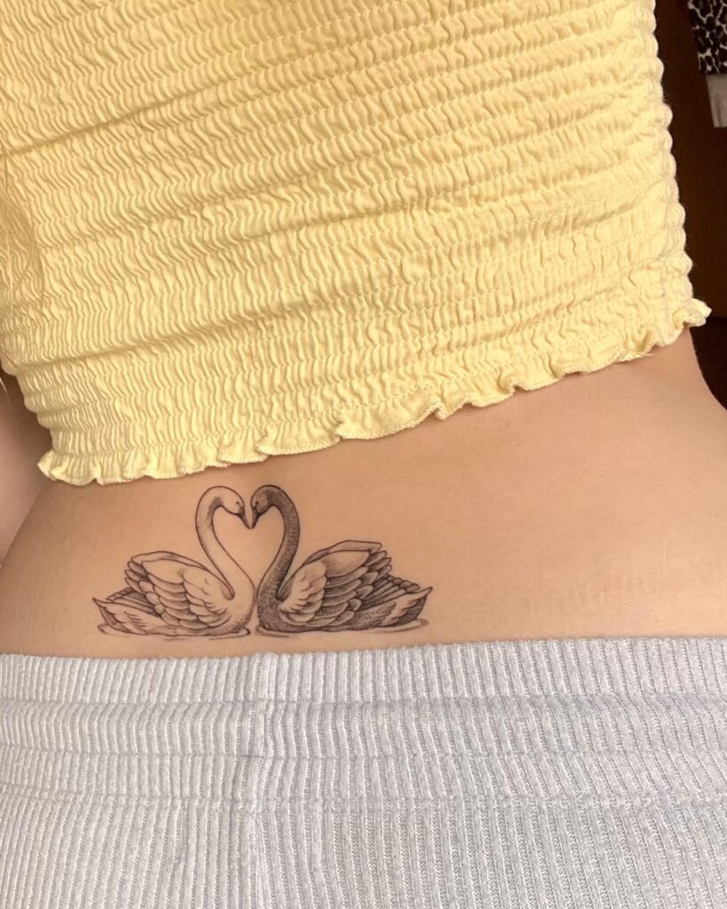 Black and Grey Tattoo on the Lower Back: Symmetrical Swan Elegance