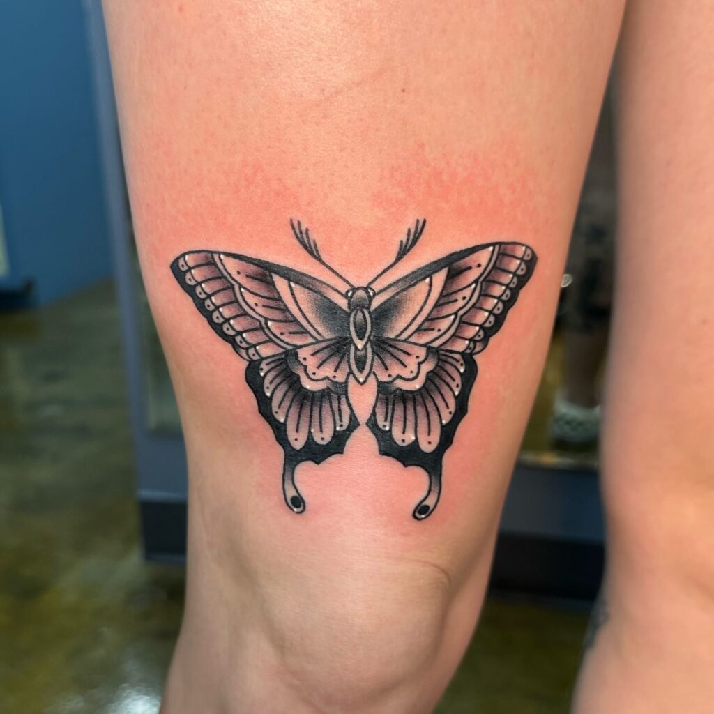 Black and white traditional butterfly tattoo on thigh timeless beauty