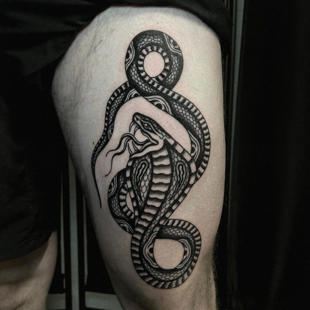 Black cobra tattoo with traditional flair on the thigh: traditional bite