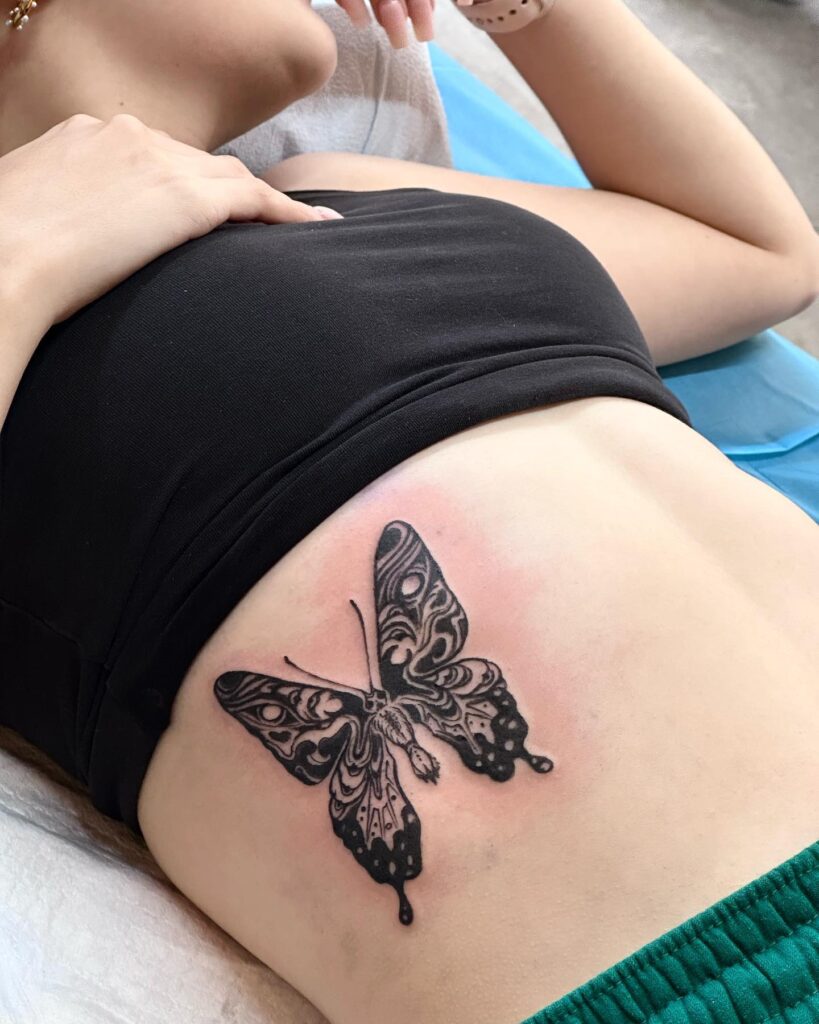 Black ink detailed butterfly tattoo on the rib for females, exquisite and detailed: butterfly ballet