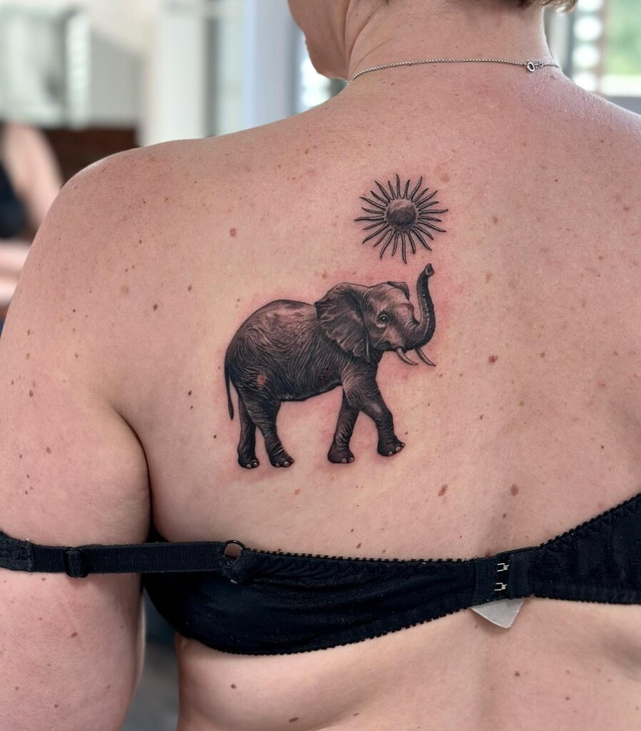 Black Work Elephant Tattoo Lifting Trunk, Side View, Above the Sun Tattoo on the Back: Back Sun Soiree
