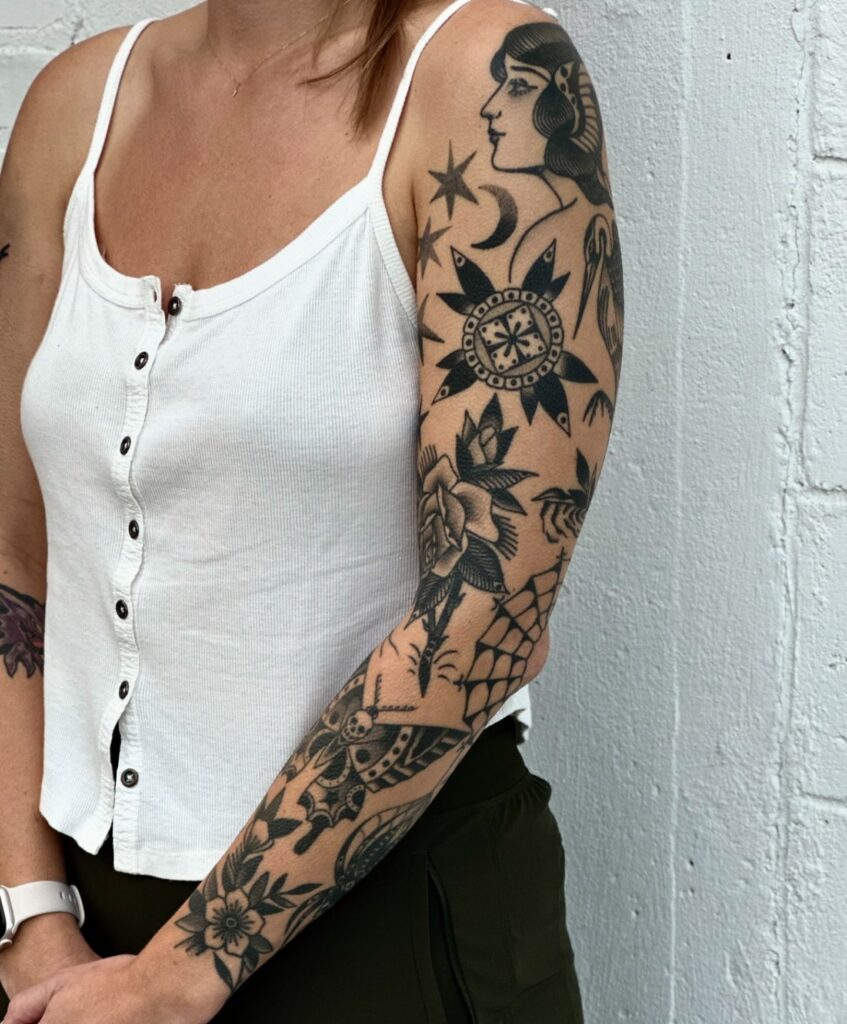 Blackwork American Traditional tattoo sleeve with celestial and floral motifs