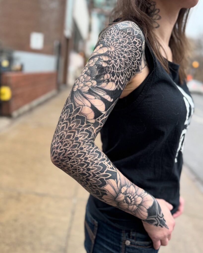 Blackwork and dotwork geometric tattoo sleeve with floral elements for women