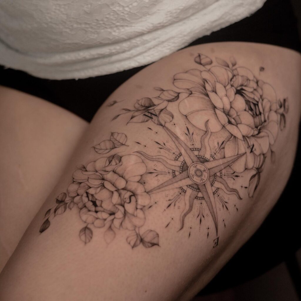 Bold and stunning floral and compass thigh tattoo nature's guidance in art