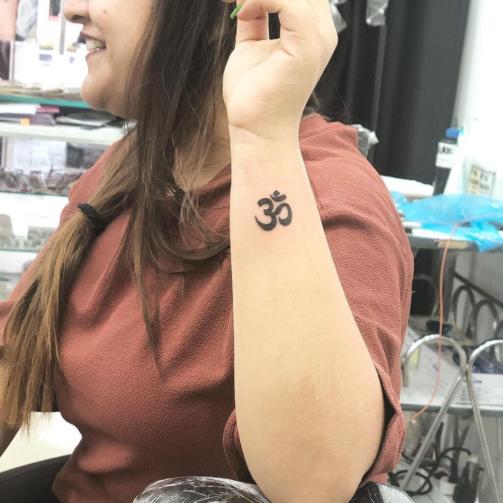 Bold black om symbol cute outer side wrist religious tattoo for females