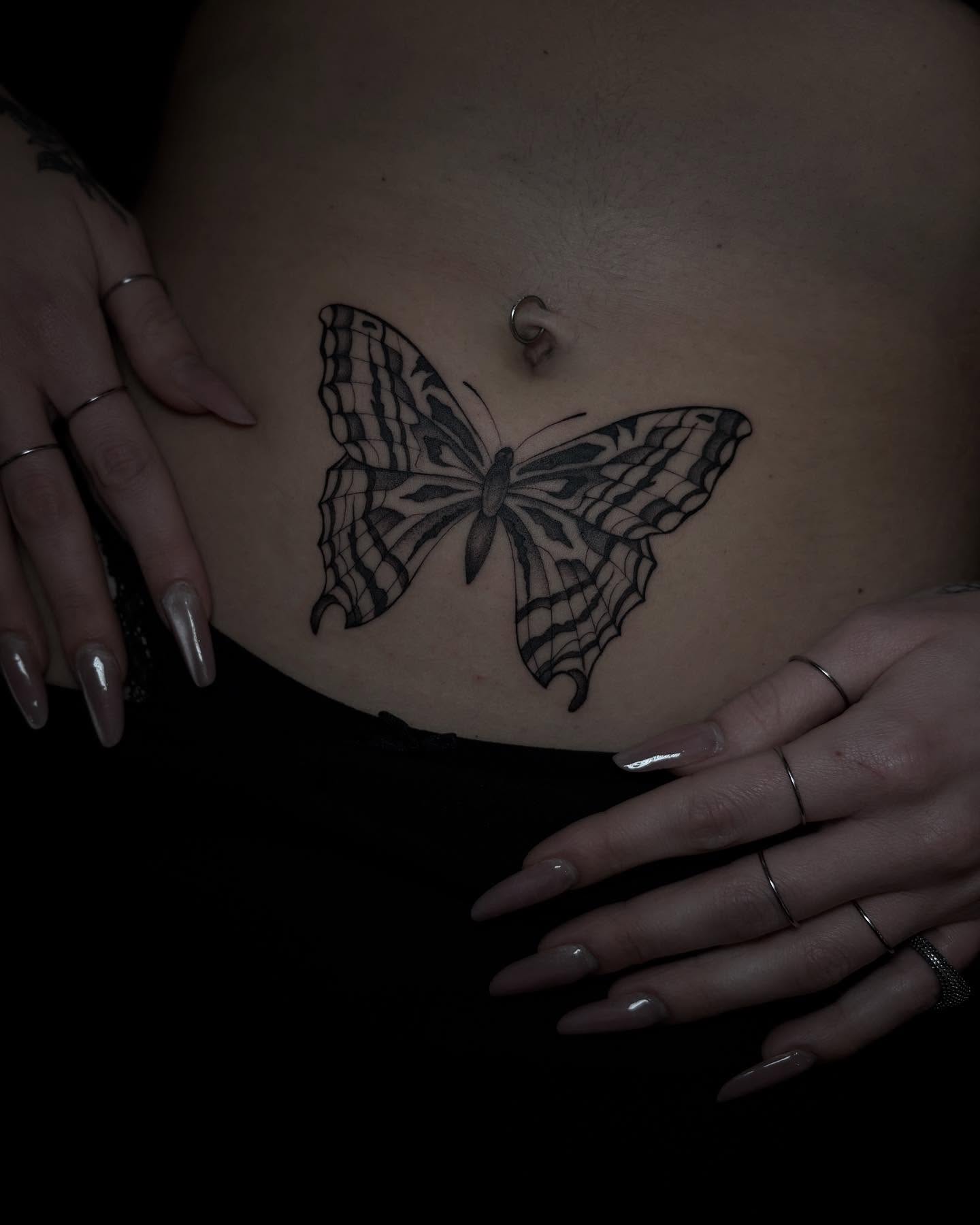 Bold butterfly tattoo below navel with symmetrical linework