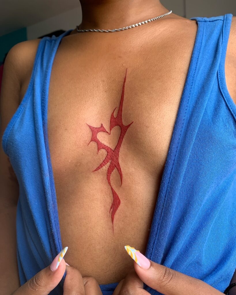 Bold red tribal-inspired sternum tattoo with a modern Y2K aesthetic