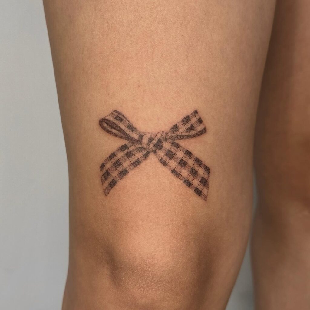 Bow ribbon tattoo above the knee: delicate and light inked elegance