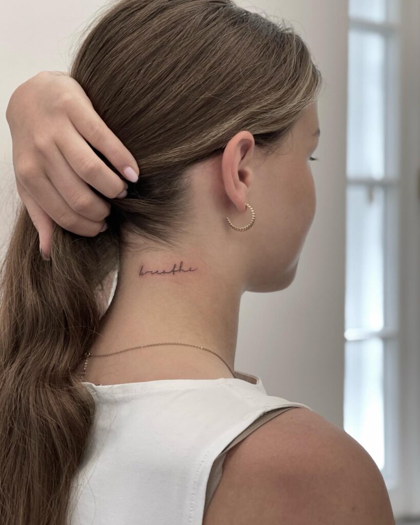 Breathe freely small lettering tattoo on the back of the neck