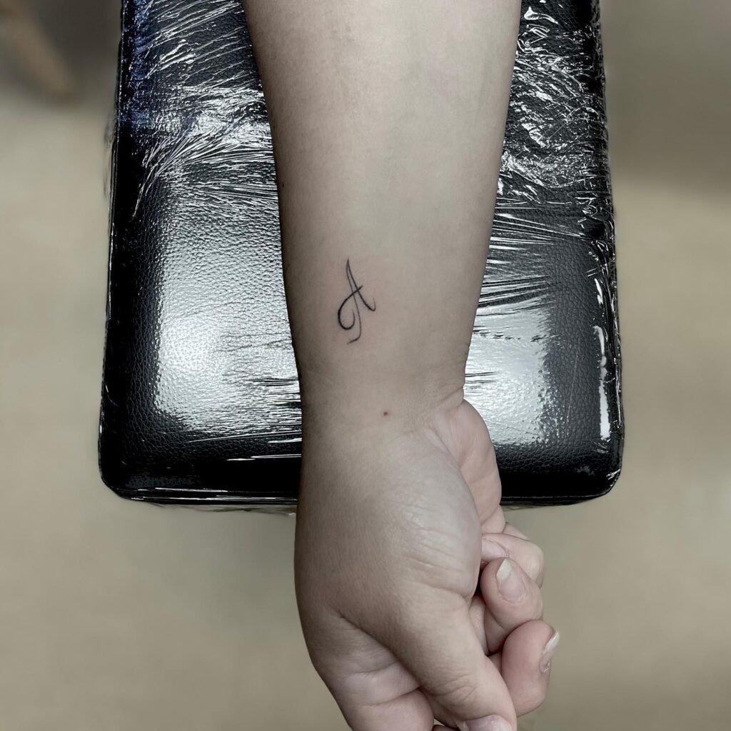 Calligraphy a letter tattoo on the side wrist a chic and simple design