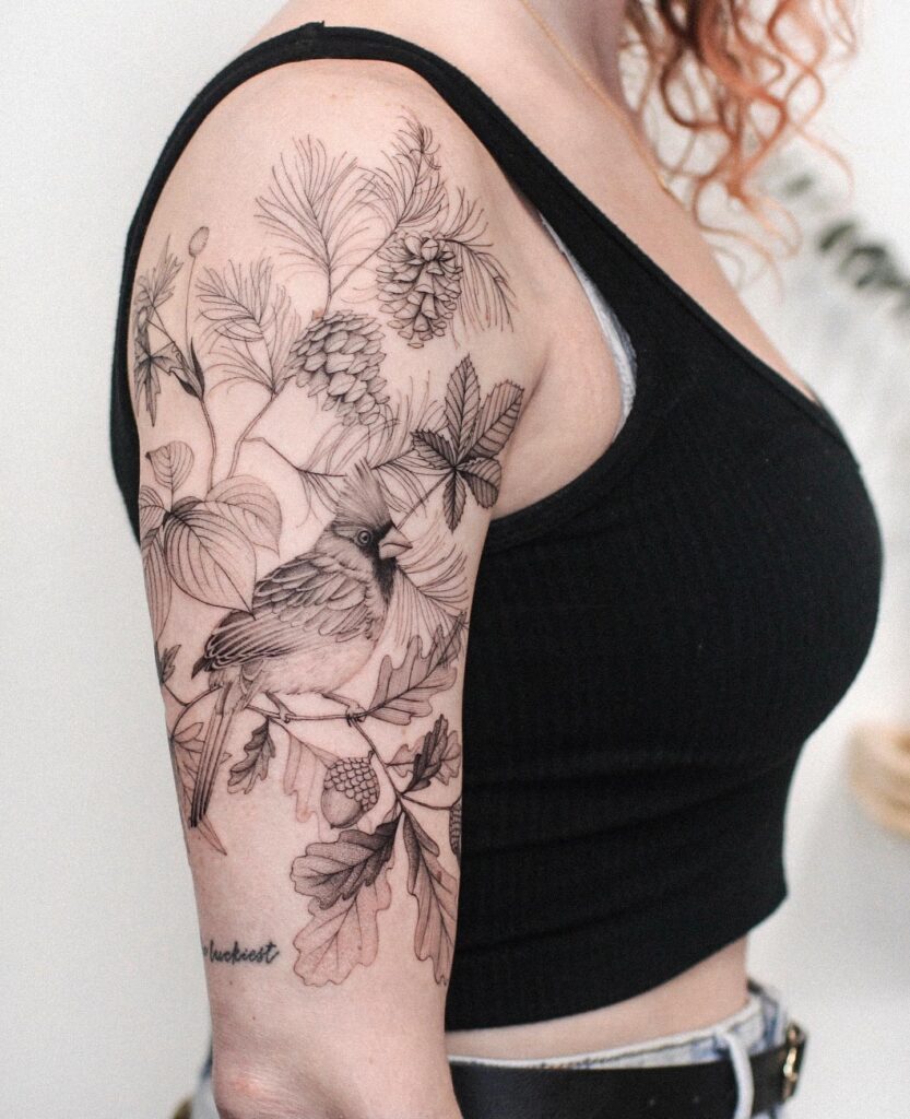 Cardinal in autumn oak tree majesty in an upper half sleeve tattoo