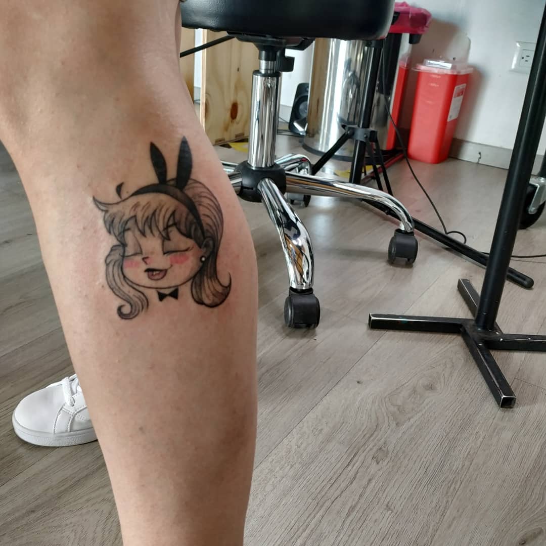 Cartoon-style bunny girl tattoo with bold black outlines, expressive facial features, and a pin-up-inspired bow tie, creating a playful and vintage aesthetic