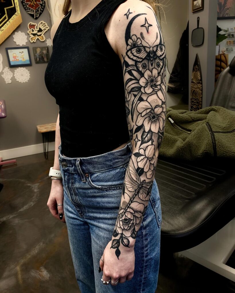 Celestial blackwork sleeve tattoo with floral and moth design
